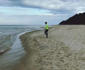 Man walking at beach against sky