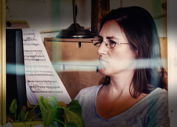 Portrait of young woman looking through window