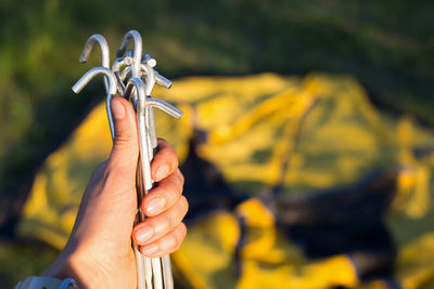 Aluminum stakes for the installation of a tourist yellow tent in the hand close-up. lightweight 