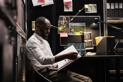 Side view of man using laptop while sitting on table