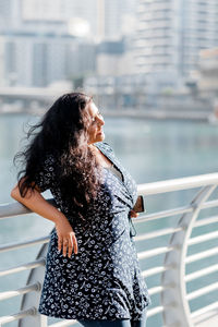 A young indian woman is walking in the dubai marina area, enjoying a sunny day