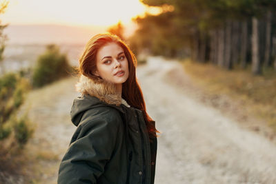 Portrait of young woman standing against black background
