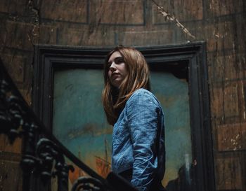 Young woman standing against wall