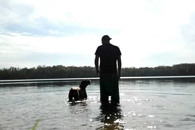 Rear view of silhouette man with dog in lake