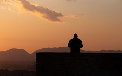 Silhouette man standing on mountain against sky during sunset