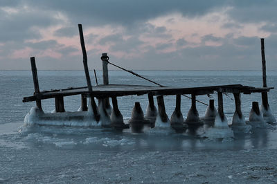 Pier over sea against sky during sunset