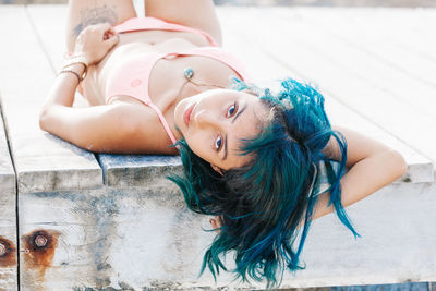 Portrait of woman in bikini lying on pier