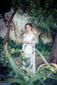 Portrait of woman standing by tree