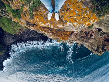 Low section of person on cliff by sea 