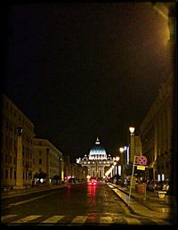 Road passing through illuminated city at night
