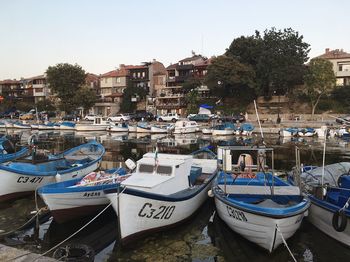 Boats moored at harbor against buildings in city