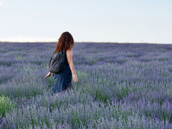 Full length of woman with flowers on field against sky