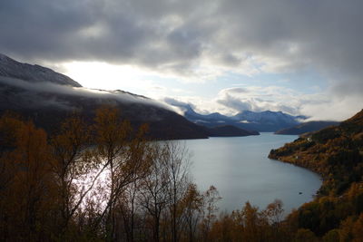 Scenic view of lake and mountains against dramatic sky