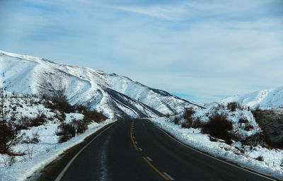 Road leading towards snowcapped mountain against sky