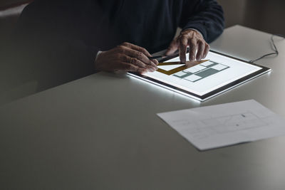 Close-up of senior man using tablet with architectural plan