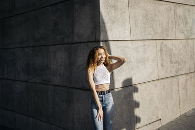 Young woman standing against wall