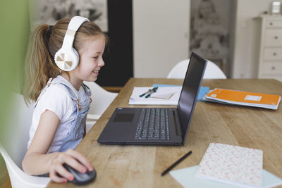 Full length of girl using laptop on table