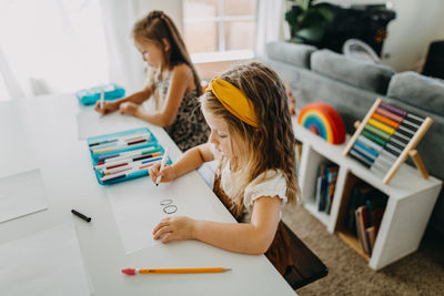 Two young girls drawing with colorful markers at table