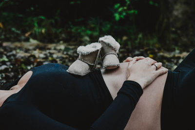Midsection of woman with shoes lying down outdoors