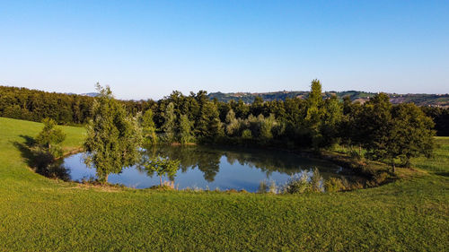 Aerial view from the drone of a little lake in italian hills with woods and meadows