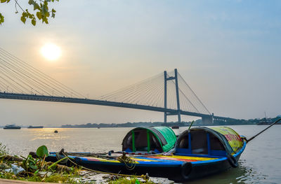 Boats moored on bridge over river against sky