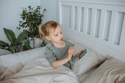 Portrait of young woman sitting on bed at home