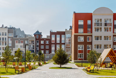 New modern green courtyard with apartment buildings with a playground, paths and benches on a sunny
