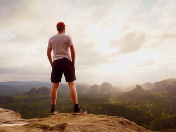 Rear view of man standing on mountain against sky