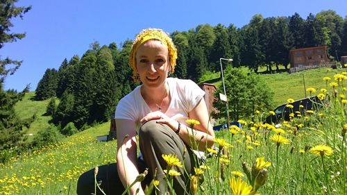 Portrait of smiling woman with yellow flower in field