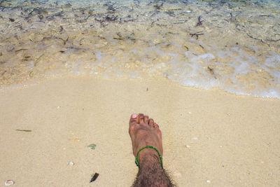 Low section of man on sand at beach