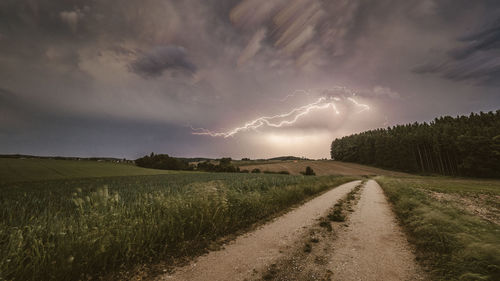 Scenic view of rural landscape against storm clouds