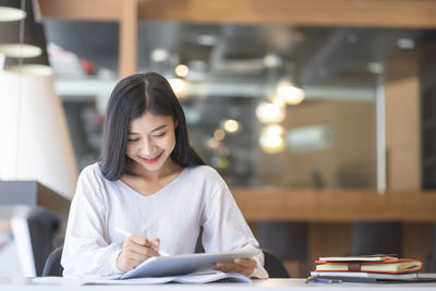 Young woman reading book on table