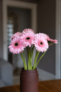 Pink flowers in a brown vase, room as background