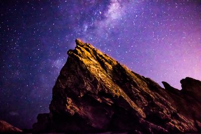 Low angle view of rock formation against sky at night