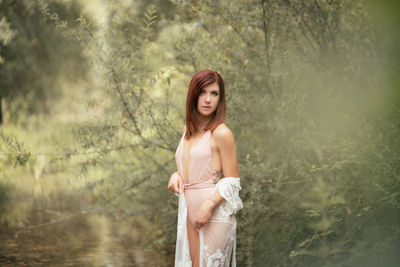 Portrait of young woman standing in forest