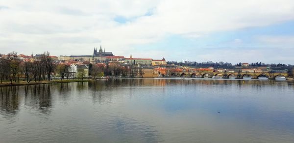 Bridge over river by buildings in city against sky