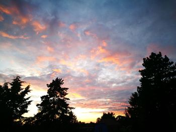 Low angle view of silhouette trees against cloudy sky