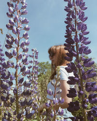 Woman standing amidst flowering plants against sky