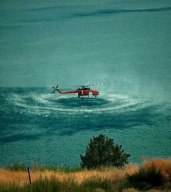 High angle view of helicopter hovering over sea