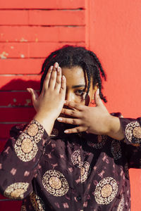 Portrait of woman against red wall