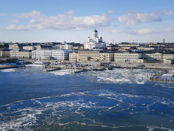 Cityscape by sea against sky