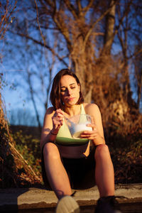 Full length of woman eating food against tree