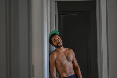 Portrait of young man leaning on wall against door