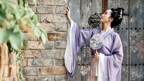 Young woman standing against brick wall