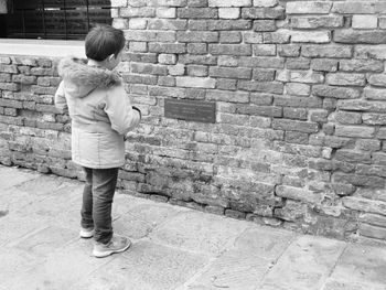 Full length of boy standing against brick wall