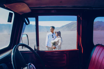 Couple standing at dessert seen through car window