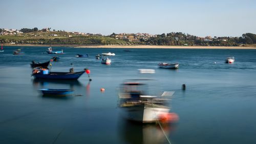 Sailboats moored on sea against clear sky