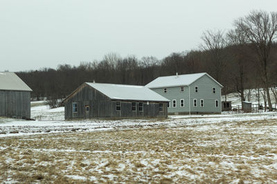 Houses on snow covered field against sky