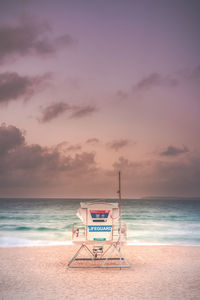 Lifeguard hut on beach against sky during sunrise