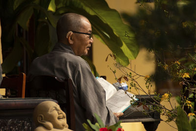 A vietnamese monk reading a book in a temple